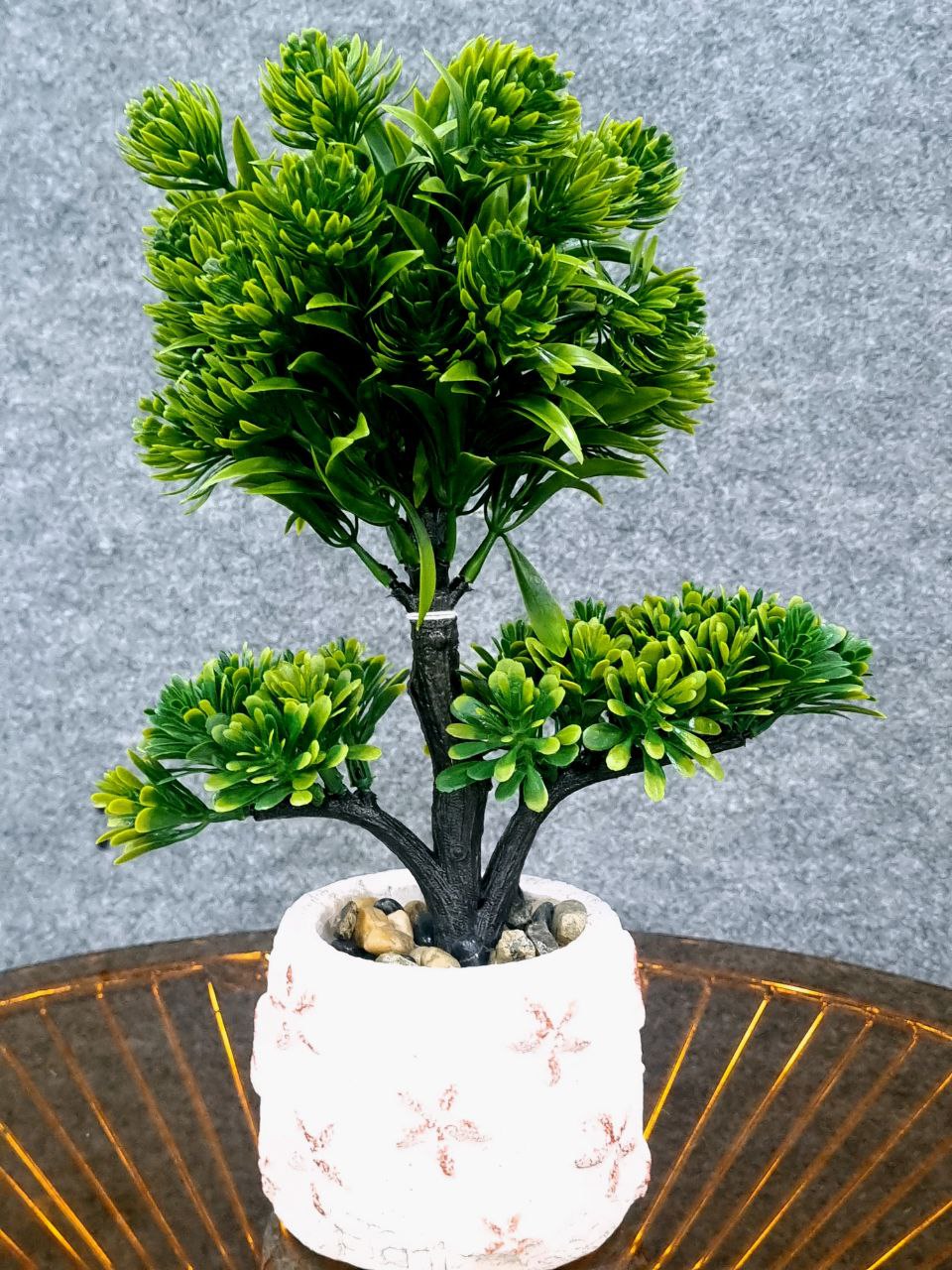 Artificial green plant in a decorative pot on a textured surface