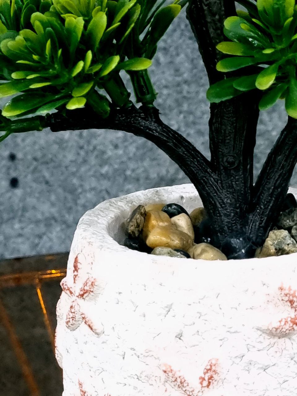 Artificial green plant in a decorative pot on a textured surface